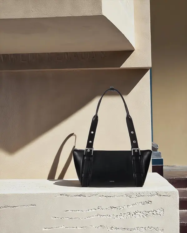 Black leather handbag animated beside sunlit stone steps