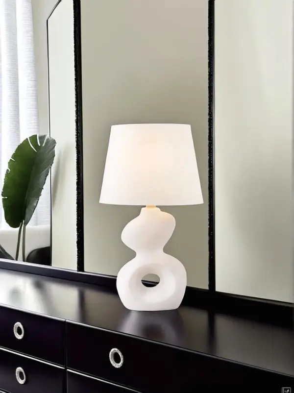 White sculptural lamp animated on a black dresser