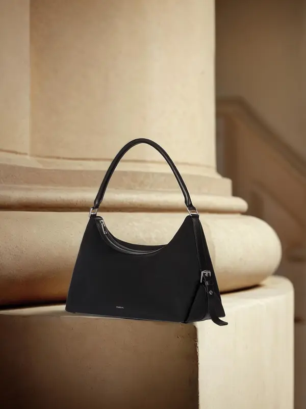 Black handbag product video on a warm stone structure